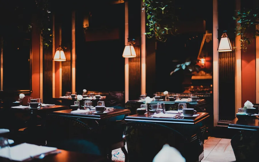 Salão de restaurante à meia-luz, com mesas postas
